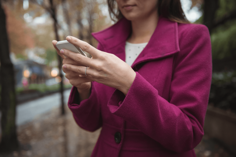 woman in purple coat holding iphone
